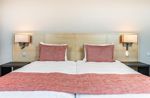 a bedroom with a large bed with two red pillows at Relais de L'Empereur in Genappe
