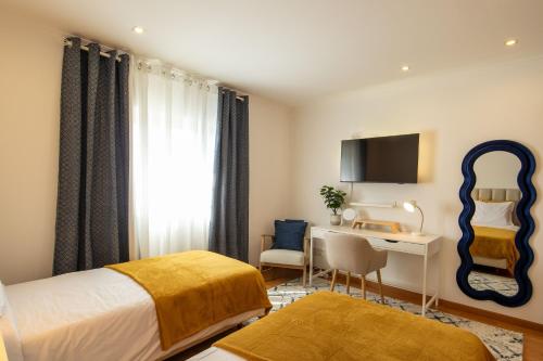 a hotel room with a bed and a desk and a television at Villa Perogil - Charming Oasis in Tavira in Tavira