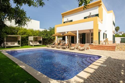 a villa with a swimming pool in front of a house at Villa Perogil - Charming Oasis in Tavira in Tavira