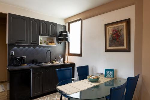 a kitchen and dining room with a glass table and blue chairs at The South Apartment In Old Town in Kastoria