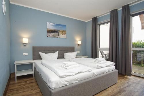 ein Schlafzimmer mit einem großen Bett mit weißer Bettwäsche in der Unterkunft strandnahe Ferienwohnung mit eigener Terrasse - Strandhaus Mönchgut FeWo 02 in Lobbe