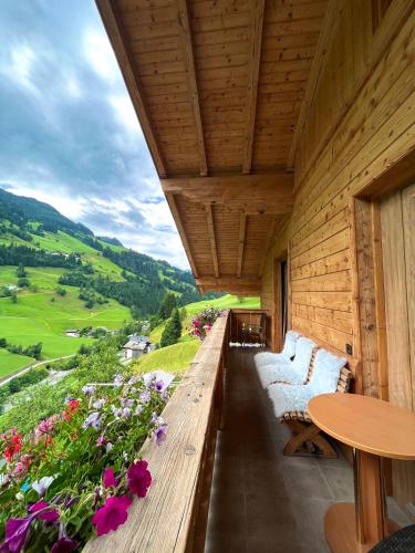 a wooden porch with couches and a table and flowers at Schaidreithof in Grossarl