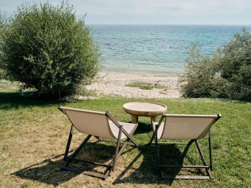 two chairs and a table next to the ocean at Mangia's Torre Del Barone Resort & SPA in Sciacca
