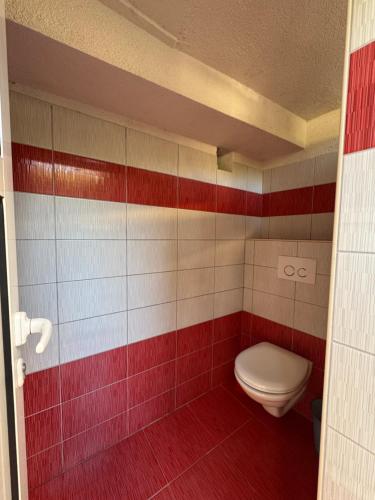 a bathroom with a toilet and red and white tiles at Autocamp Panorama in Grebaštica