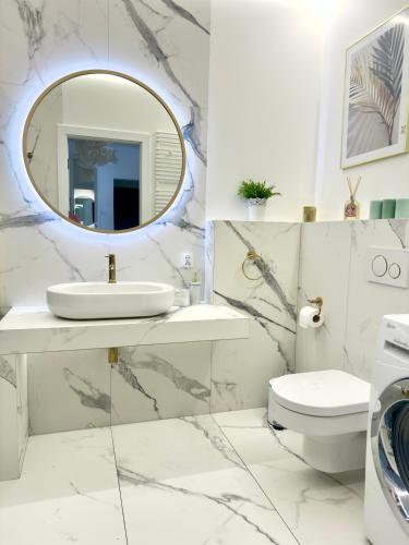 een witte badkamer met een wastafel en een spiegel bij Apartament Portowy in Giżycko