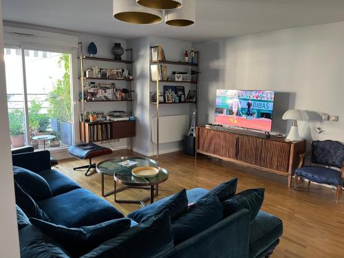 a living room with a blue couch and a tv at Chambre et salle de bains autonome dans un logement élégant in Courbevoie