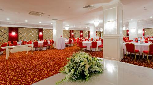 a banquet hall with white tables and red chairs at Svalinn Hotel in Izmir