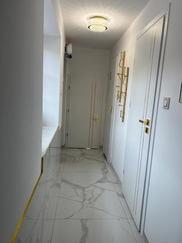 a hallway with white walls and a tile floor at GOLD Apartment in Święta Katarzyna