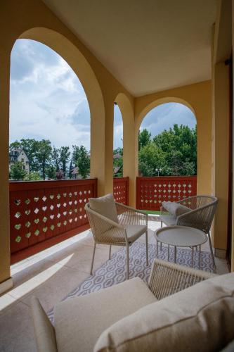 a patio with chairs and tables on a balcony at JEZERSKA RESIDENCE Palić in Palić