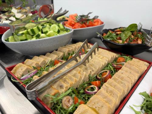 a buffet with sandwiches and salads and bowls of vegetables at Apartamenty Rondo in Świnoujście
