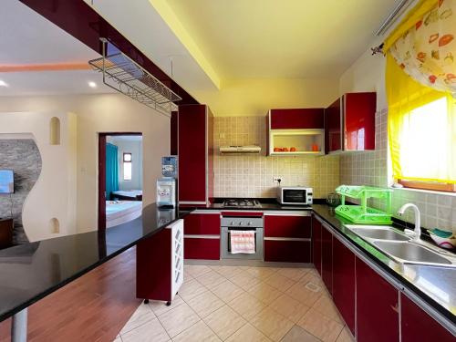 Una cocina con gabinetes rojos y un fregadero. en Usiku Mwema Beachfront Apartments, en Mombasa
