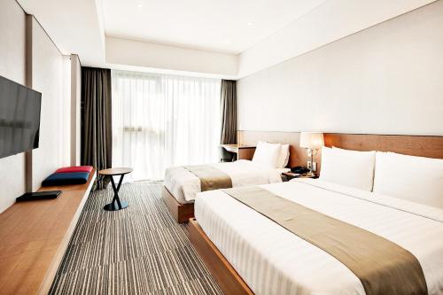 a hotel room with two beds and a flat screen tv at Golden Tulip Incheon Airport Hotel in Incheon