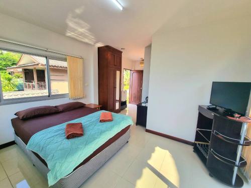 a bedroom with a bed and a flat screen tv at Floral House in Lamai