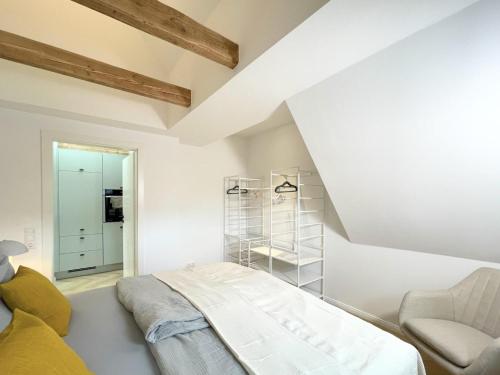 a white room with a bed and a chair at FRITZ21 Ferienwohnung Kellenhusen in Kellenhusen