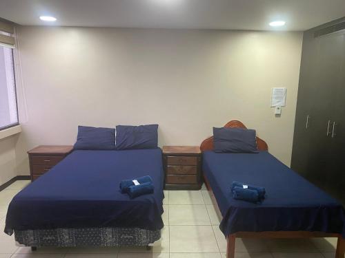 two beds in a room with blue sheets at Puerto Santa Ana, Torres Bellini, 2 dormitorios, Parqueo in Guayaquil
