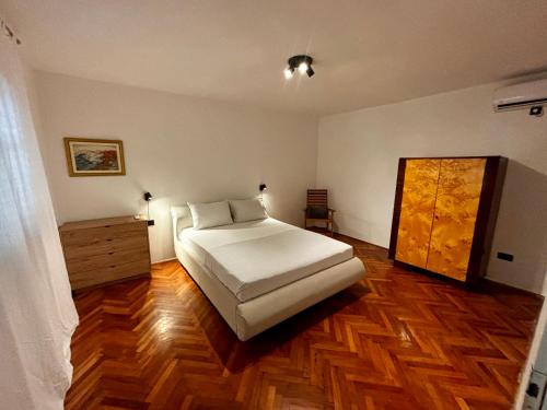 a bedroom with a white bed and a wooden floor at Mandarin Garden House in Orebić
