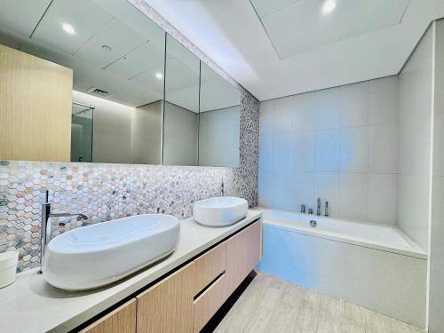 a bathroom with a sink and a tub and a mirror at Circuit Views 1BR in Mayan 1 in Abu Dhabi