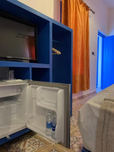 a blue cabinet with a tv and water bottles in it at Chez Youssef in Merzouga