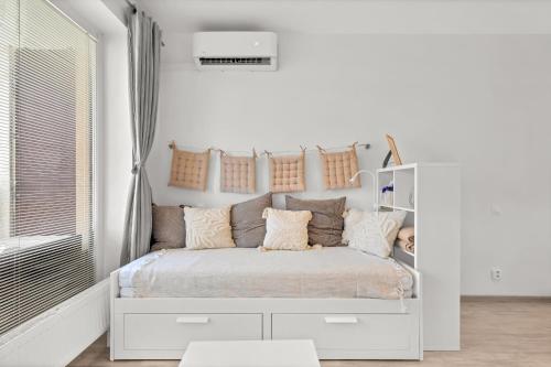 a white bedroom with a white bed with pillows at Slnecnice studio with parking and 24 hour check in in Bratislava