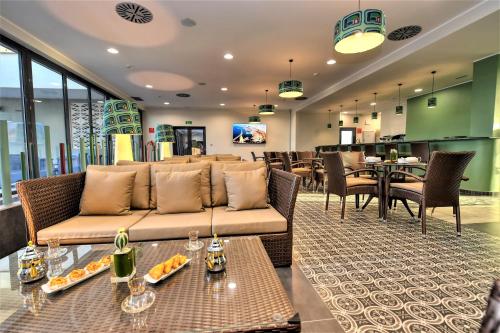 ein Wohnzimmer mit einer Couch sowie Tischen und Stühlen in der Unterkunft Hotel Falcon Thalassa Resort & SPA in Aïn El Turk