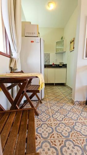 a kitchen with a wooden table and a refrigerator at Morro Branco Pousada e aptos in Natal
