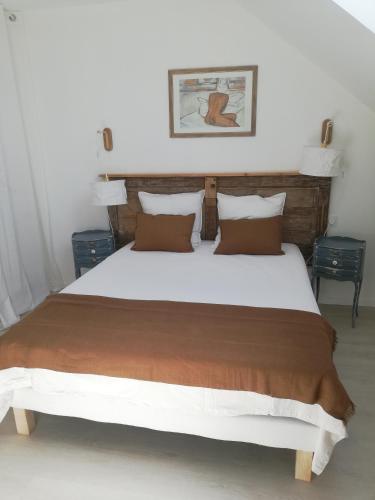 1 dormitorio con 1 cama blanca grande con almohadas marrones en La mansarde, en Nozay