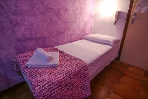a small room with a bed with a towel on a table at Hotel Luina in Stresa