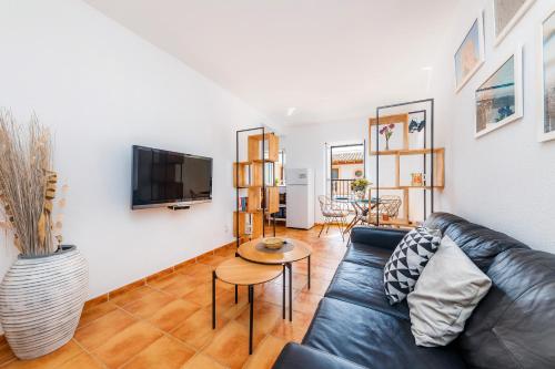 a living room with a black leather couch and a table at Apartamento Can Jaume in Artá
