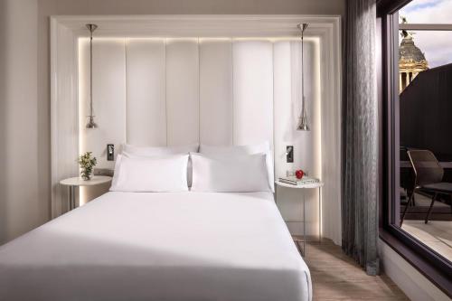 a bedroom with a large white bed and a window at NH Collection Barcelona Gran Hotel Calderon in Barcelona