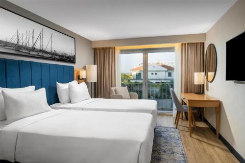 a hotel room with two beds and a desk at Radisson Blu Resort & Spa Cesme in Cesme