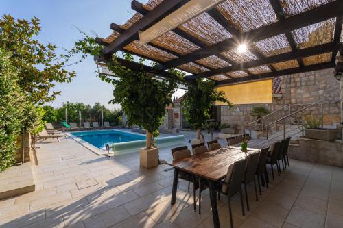 a patio with a table and chairs and a pool at Villa Joe in Čilipi