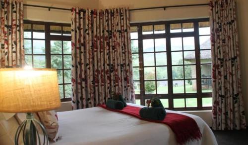 una camera da letto con un letto con una lampada e finestre di Fairways at Drakensberg Gardens Resort Timeshare a Underberg