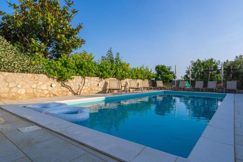 a swimming pool with chairs and a wall at Villa Joe in Čilipi