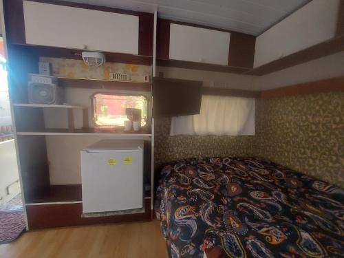 a small bedroom with a bed and a tv at Pousada e Camping Tio Wil in Extrema