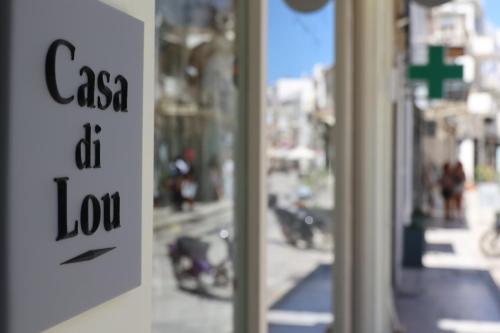 a sign in a store window with a motorcycle in the background at Casa di Lou in Ermoupoli