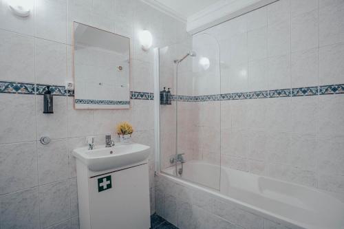 ein weißes Badezimmer mit Waschbecken und Badewanne in der Unterkunft Yellow House - Casa 2 in Angra do Heroísmo