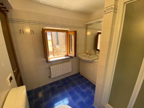 Un baño con inodoro, lavabo y ventana. en Appartamento Fiaschi, en San Gimignano