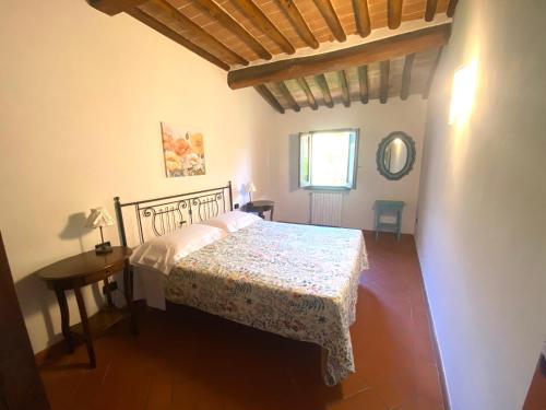 Un dormitorio con una cama y una mesa y una ventana. en Appartamento Fiaschi, en San Gimignano