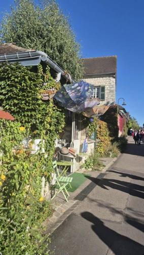 a house with an umbrella and a table and chairs at Gîte pres de Giverny in Gasny