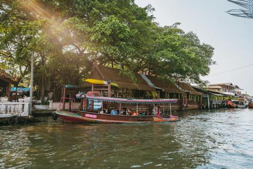 a boat on a river with people on it at Arpo Pool Villa Riverside Bangkok in Bangkok