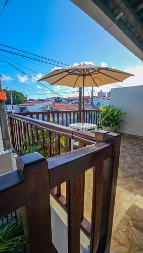 a balcony with a table and an umbrella at Morro Branco Pousada e aptos in Natal