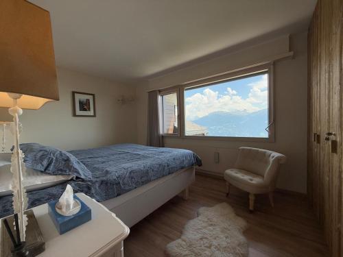 a bedroom with a bed and a window and a chair at Crans-Montana luxury duplex ,Swiss Alps in Crans-Montana