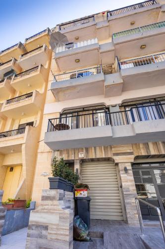 an apartment building with a garage in front of it at WalkTo Beach & Restaurant by QuickTrips in St Paul's Bay