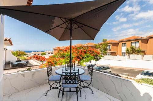 a table and chairs on a balcony with an umbrella at The Skippers Nest in San Miguel de Abona