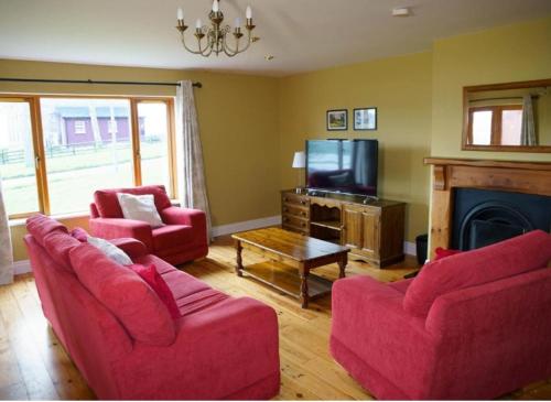a living room with two red couches and a tv at Dingle Courtyard Holiday Homes 3 Bed Sleeps 6 in Dingle