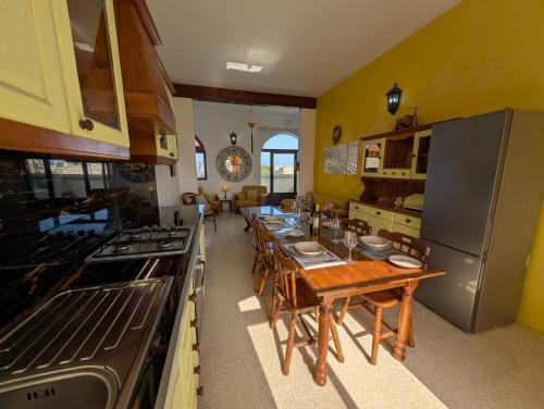 a kitchen with a long table with chairs and a stove at Tal Jordan Complex in Għarb