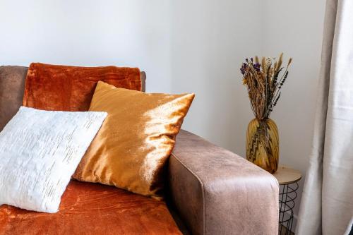 - un canapé avec deux oreillers et un vase de fleurs dans l'établissement Le Mana, 7 pers 2 chambres 12min Disneyland Paris, à Bailly-Romainvilliers