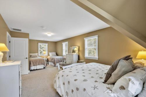 ein Schlafzimmer mit einem großen Bett und ein Zimmer in der Unterkunft Spacious 7 Bed Retreat with Game Room, Deck, Yard, Half a Block from Ocean, Host Up to 22 Across 16 Beds, Gas Fireplace, Gas Grill, Ample Parking, Walk to Menauhant Beach, 24 Hr Hospitality in Falmouth