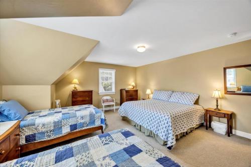 ein Schlafzimmer mit zwei Betten und einem Spiegel in der Unterkunft Spacious 7 Bed Retreat with Game Room, Deck, Yard, Half a Block from Ocean, Host Up to 22 Across 16 Beds, Gas Fireplace, Gas Grill, Ample Parking, Walk to Menauhant Beach, 24 Hr Hospitality in Falmouth