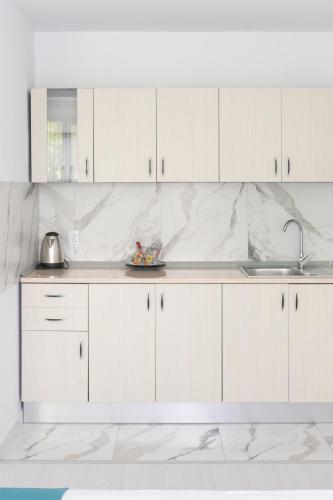 a white kitchen with white cabinets and a sink at Hotel Palas Grand View in Iaşi